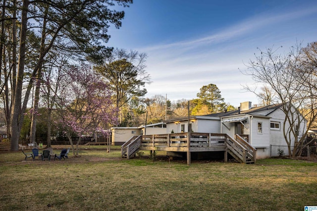 back of house with a fire pit, a chimney, stairs, a deck, and a yard