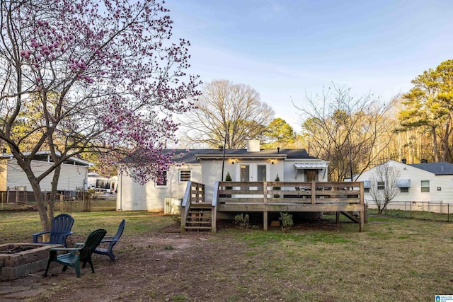 back of house featuring a fire pit, a deck, a chimney, and fence