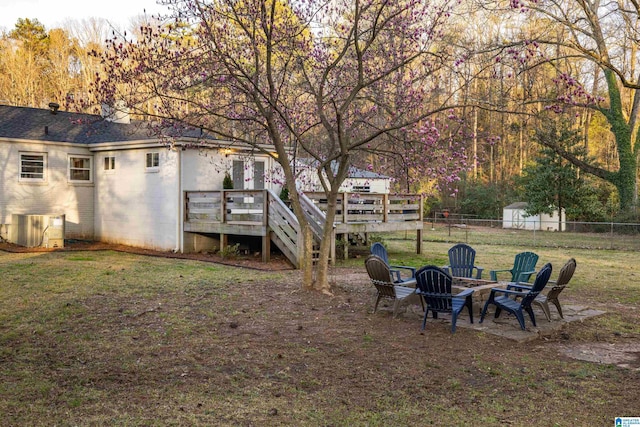 view of yard with a deck, an outdoor fire pit, central AC unit, and fence