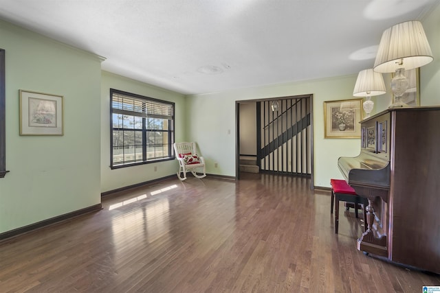 living room featuring dark wood-style flooring, crown molding, baseboards, and stairs