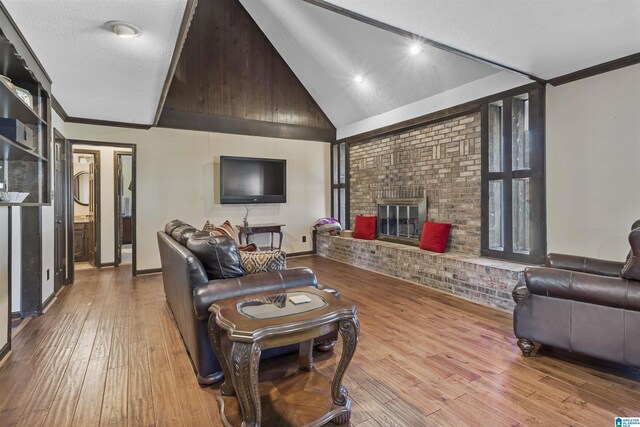 living area featuring crown molding, a fireplace, a textured ceiling, brick wall, and light wood-type flooring