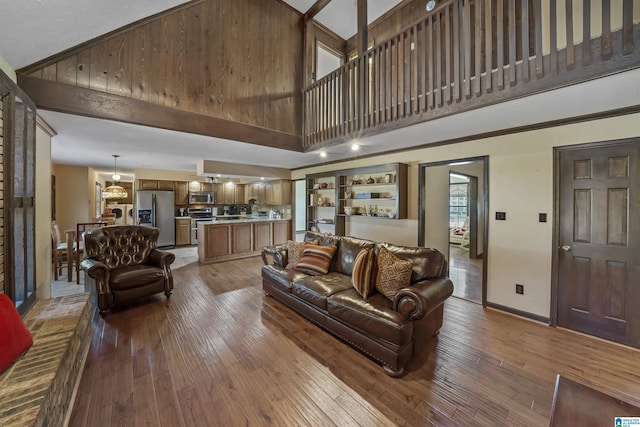 living area with baseboards, a high ceiling, and wood finished floors