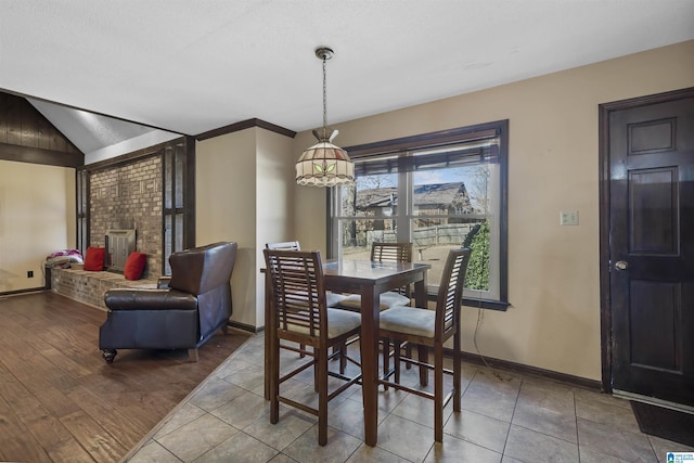 dining room featuring vaulted ceiling, a textured ceiling, baseboards, and wood finished floors