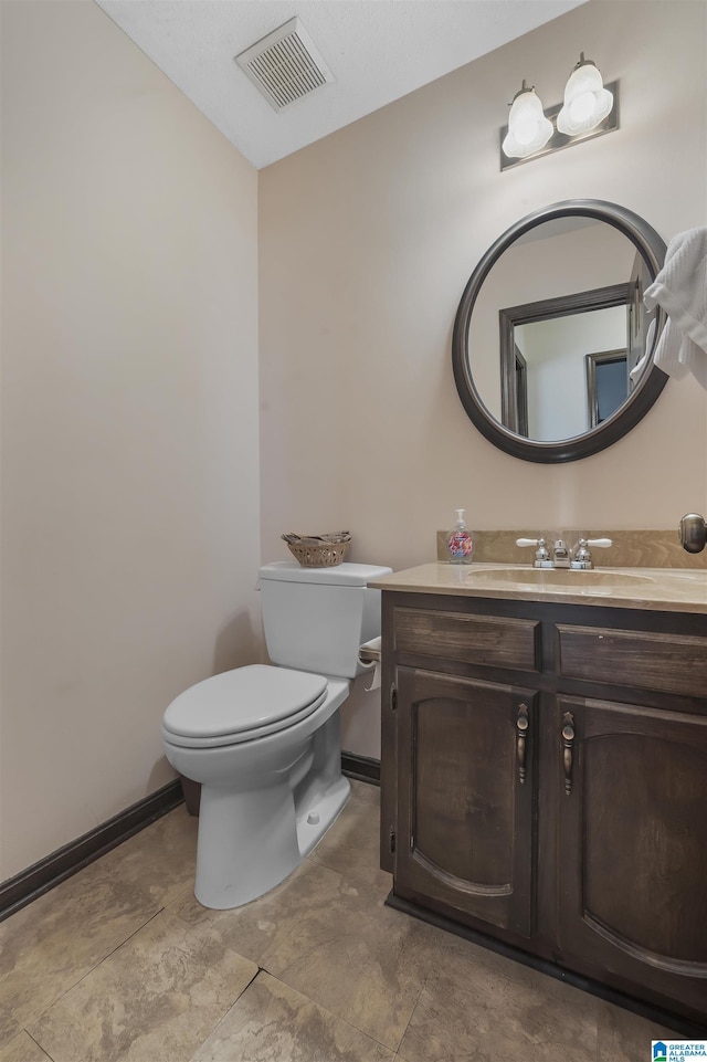 half bathroom featuring baseboards, visible vents, vanity, and toilet