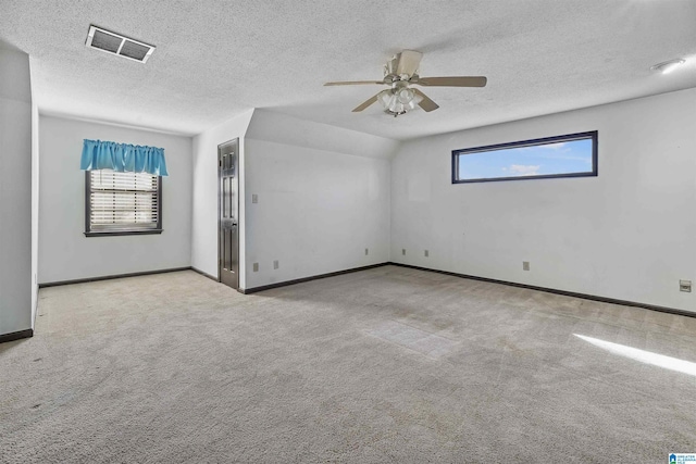 empty room with a wealth of natural light, visible vents, light carpet, and baseboards