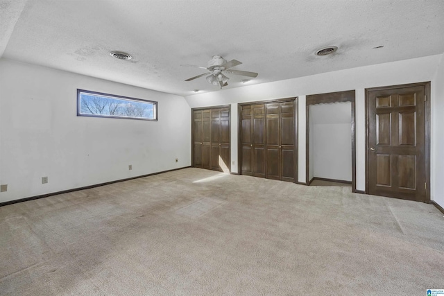 unfurnished bedroom featuring light carpet, visible vents, and multiple closets