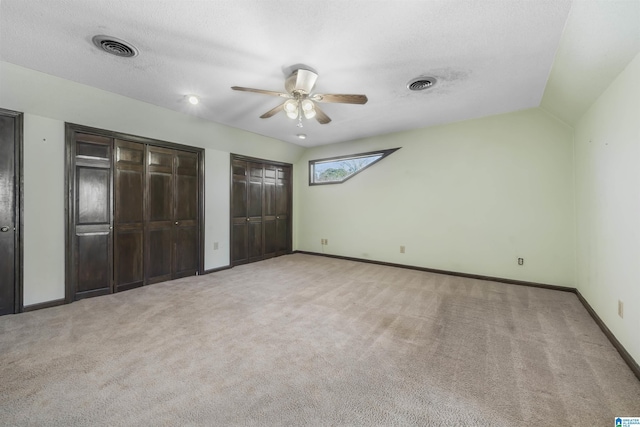 unfurnished bedroom featuring baseboards, visible vents, two closets, and carpet flooring