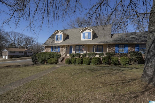 cape cod home with brick siding, a porch, and a front yard