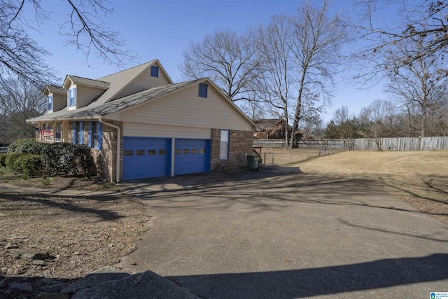 view of property exterior with a garage, fence, aphalt driveway, and brick siding