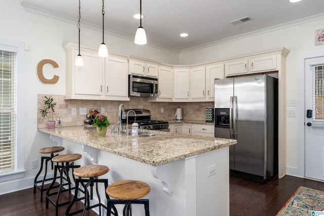 kitchen featuring light stone counters, decorative light fixtures, stainless steel appliances, visible vents, and a peninsula