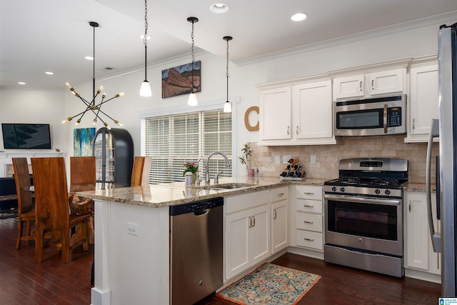 kitchen with stainless steel appliances, white cabinets, a sink, and hanging light fixtures