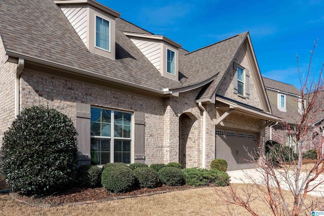 exterior space featuring a garage, a shingled roof, and brick siding