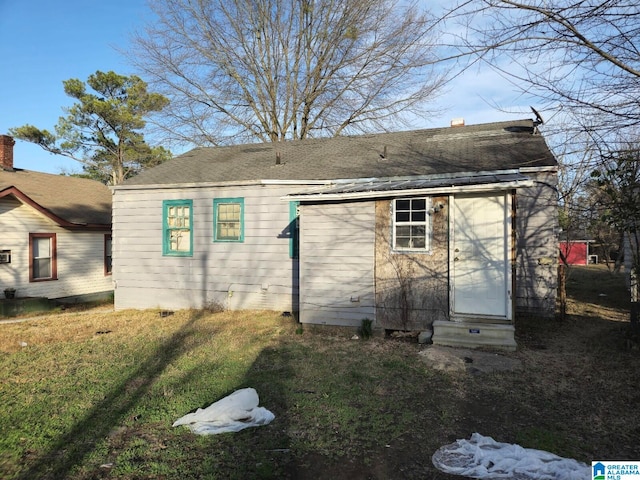 back of property featuring entry steps and a yard