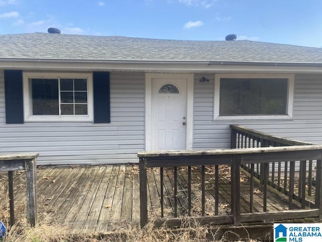 property entrance featuring a deck and roof with shingles