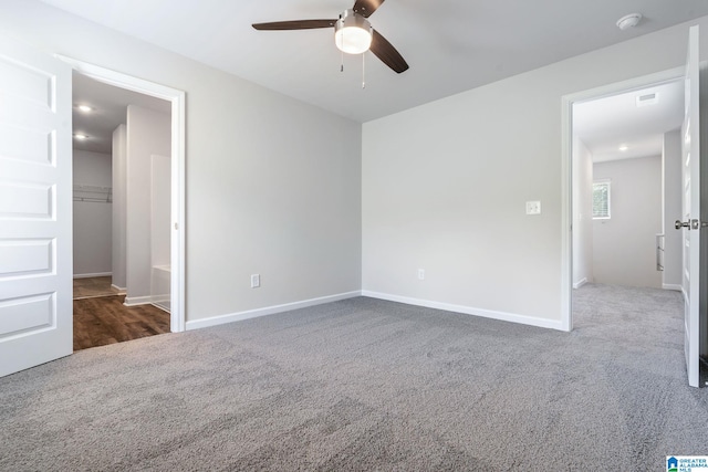 unfurnished bedroom with baseboards, dark colored carpet, and a ceiling fan