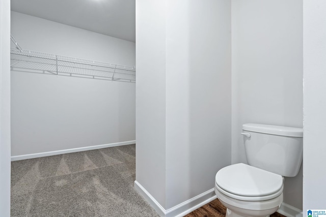 bathroom featuring toilet, a spacious closet, and baseboards