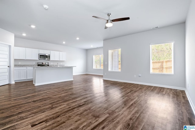 unfurnished living room with ceiling fan, recessed lighting, dark wood finished floors, and baseboards