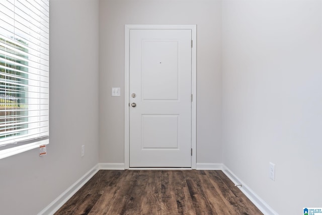 doorway with dark wood finished floors and baseboards