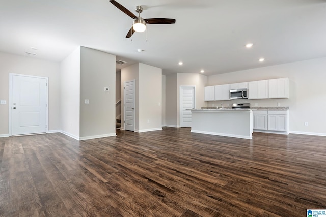 unfurnished living room featuring dark wood-style flooring, recessed lighting, stairway, ceiling fan, and baseboards