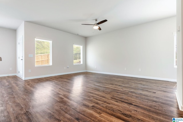 empty room featuring dark wood-type flooring, baseboards, and a ceiling fan