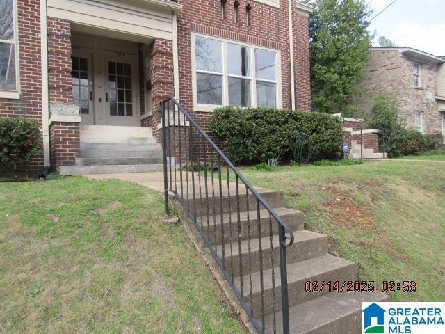 doorway to property with brick siding and a yard