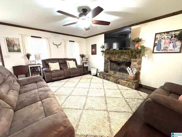 living room featuring baseboards, ornamental molding, a ceiling fan, and a stone fireplace