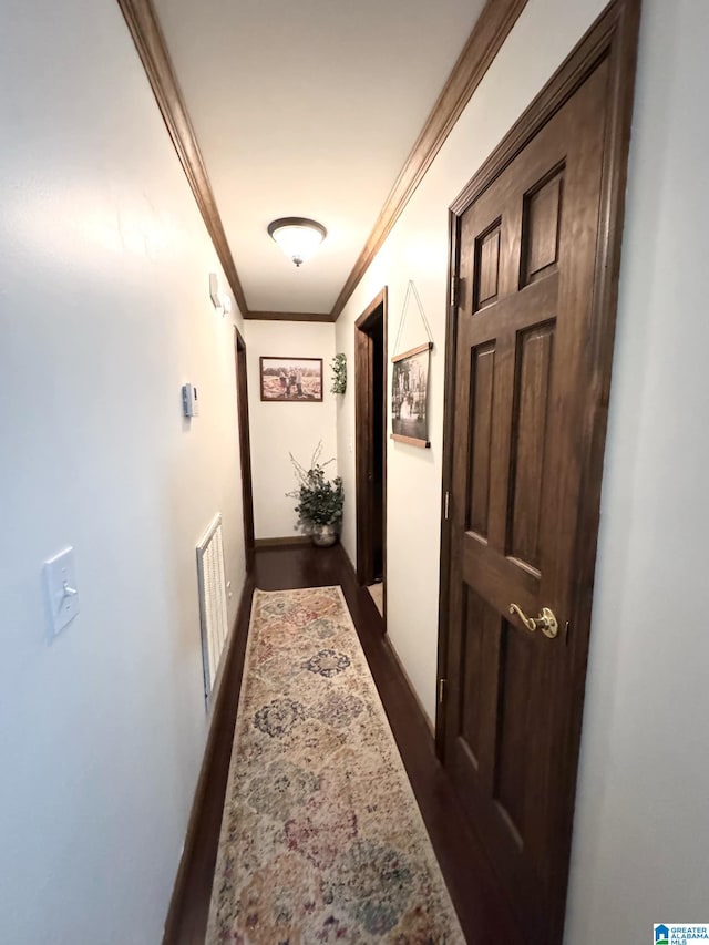 corridor with baseboards, visible vents, ornamental molding, and dark wood-style flooring