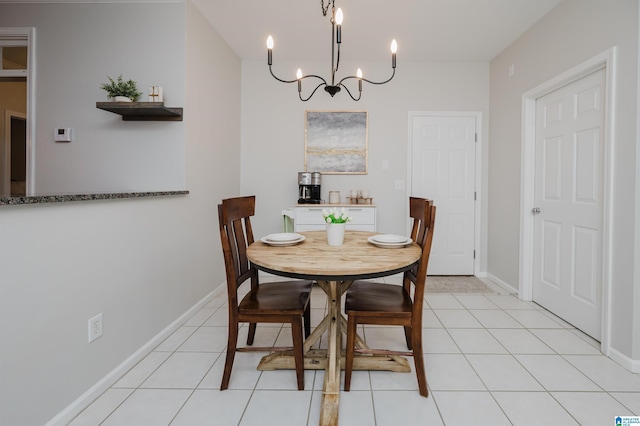 dining area featuring light tile patterned flooring, a notable chandelier, and baseboards