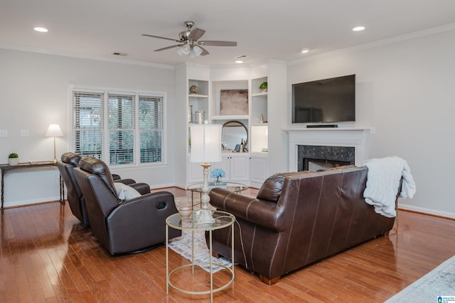 living area with ornamental molding, a fireplace, wood finished floors, and baseboards