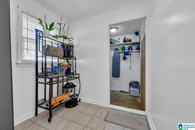 corridor with ornamental molding, light tile patterned flooring, and baseboards