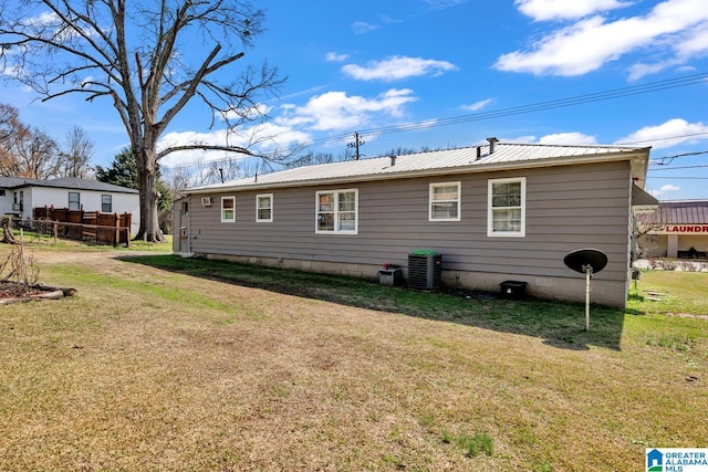 back of property featuring metal roof, cooling unit, and a yard