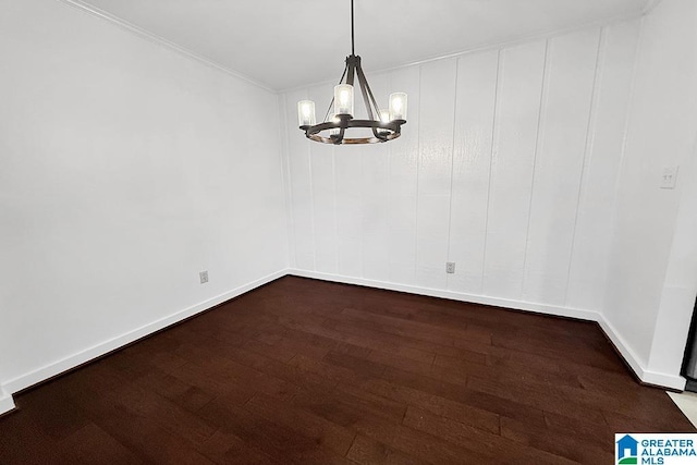 unfurnished room with a notable chandelier, baseboards, and wood finished floors