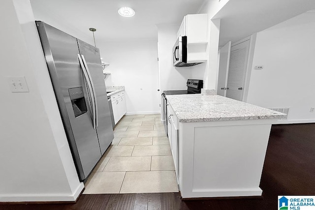 kitchen with light tile patterned floors, stainless steel appliances, white cabinets, hanging light fixtures, and light stone countertops