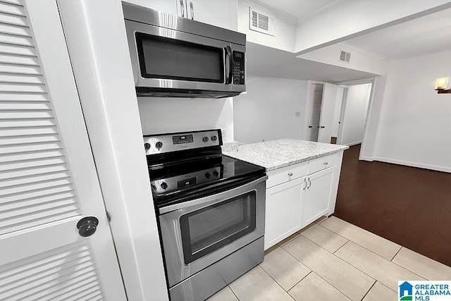 kitchen with light tile patterned floors, stainless steel appliances, visible vents, white cabinetry, and light stone countertops