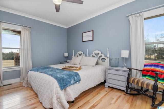 bedroom with light wood-style flooring, multiple windows, ornamental molding, and a ceiling fan