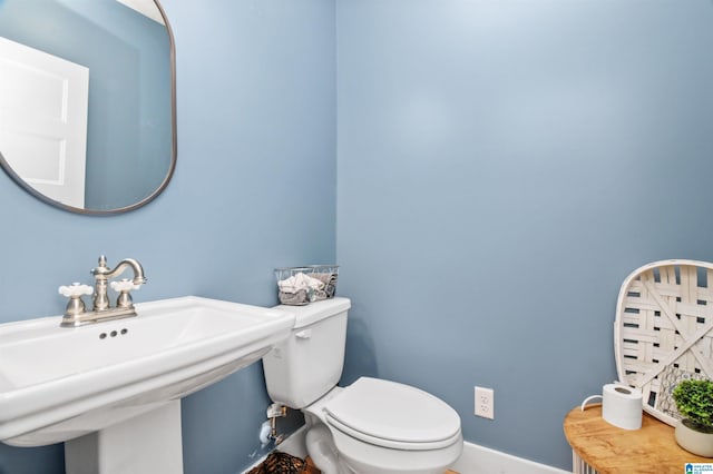 bathroom with toilet, baseboards, and a sink