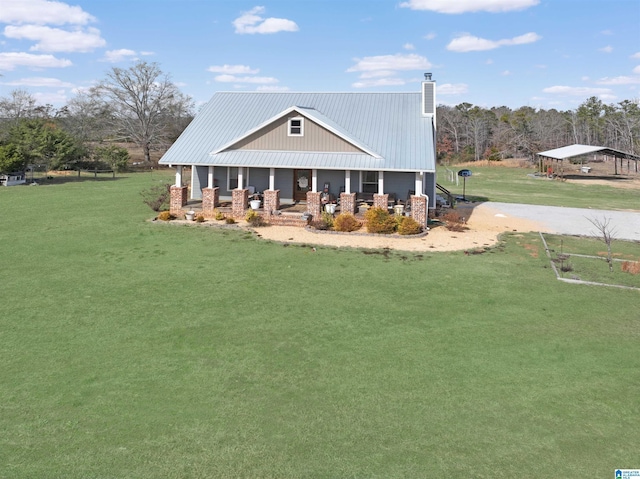 exterior space featuring metal roof, a porch, a front lawn, and a chimney