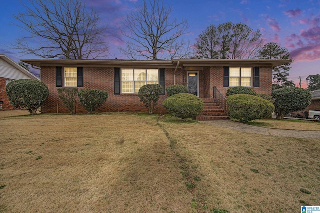 ranch-style house featuring brick siding and a lawn