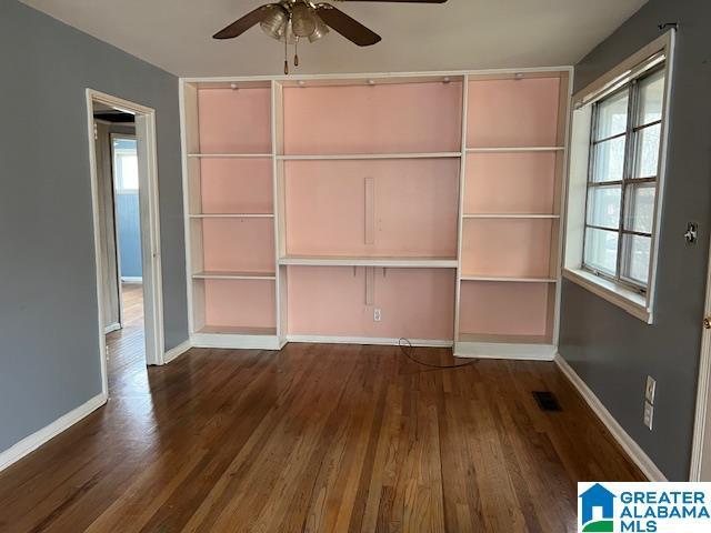 unfurnished bedroom featuring dark wood-type flooring, visible vents, ceiling fan, and baseboards