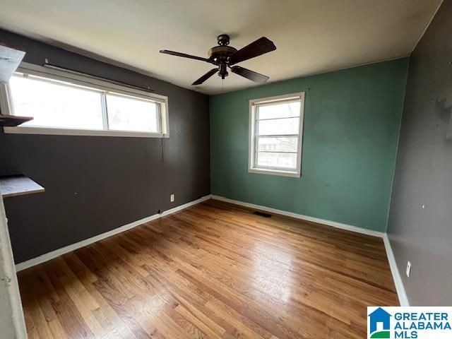 empty room featuring ceiling fan, wood finished floors, and baseboards