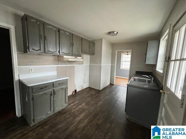 kitchen featuring gray cabinetry, dark wood-style flooring, a sink, and light countertops