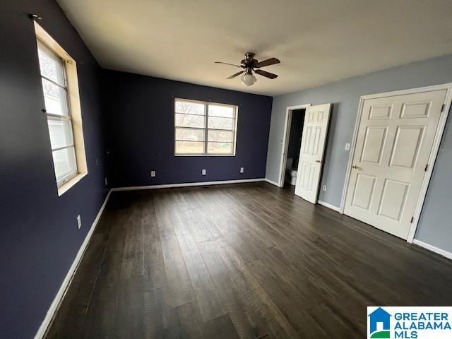 unfurnished bedroom with baseboards, dark wood finished floors, and a ceiling fan