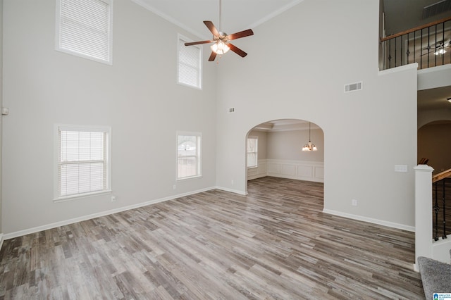 unfurnished living room featuring visible vents, crown molding, arched walkways, and wood finished floors