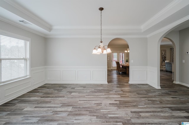 unfurnished room with arched walkways, visible vents, wainscoting, wood finished floors, and a chandelier