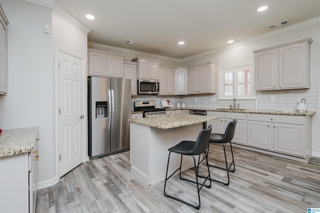 kitchen with visible vents, appliances with stainless steel finishes, a sink, and ornamental molding