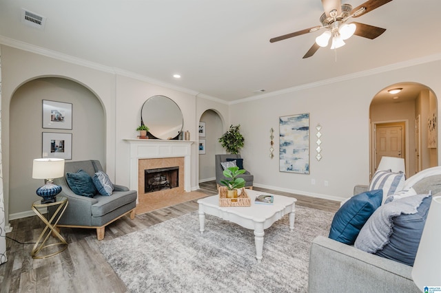 living area featuring a tile fireplace, visible vents, light wood-style flooring, and baseboards