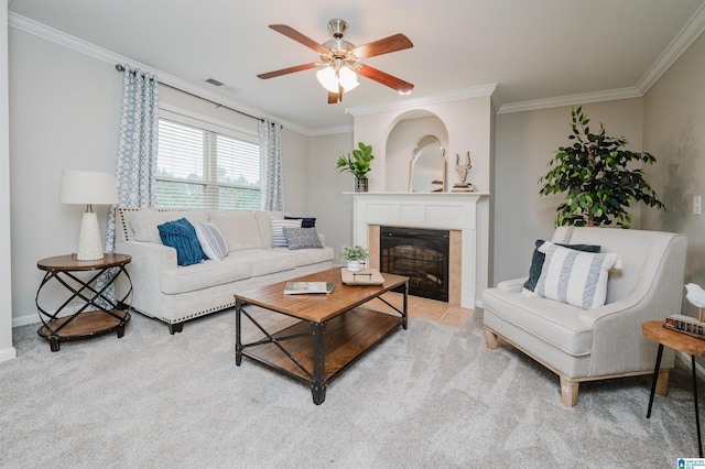 living area with ceiling fan, ornamental molding, light colored carpet, and a glass covered fireplace