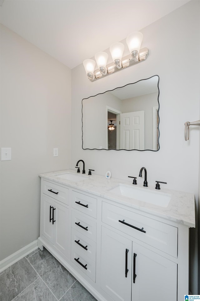 full bathroom with a sink, baseboards, and double vanity