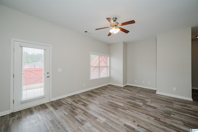 empty room featuring baseboards, visible vents, ceiling fan, and wood finished floors