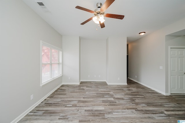 empty room featuring ceiling fan, wood finished floors, visible vents, and baseboards